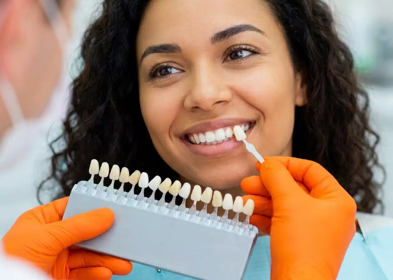 Paciente sorrindo ao escolher a cor da lente de contato dental com escala de cores na DENT+